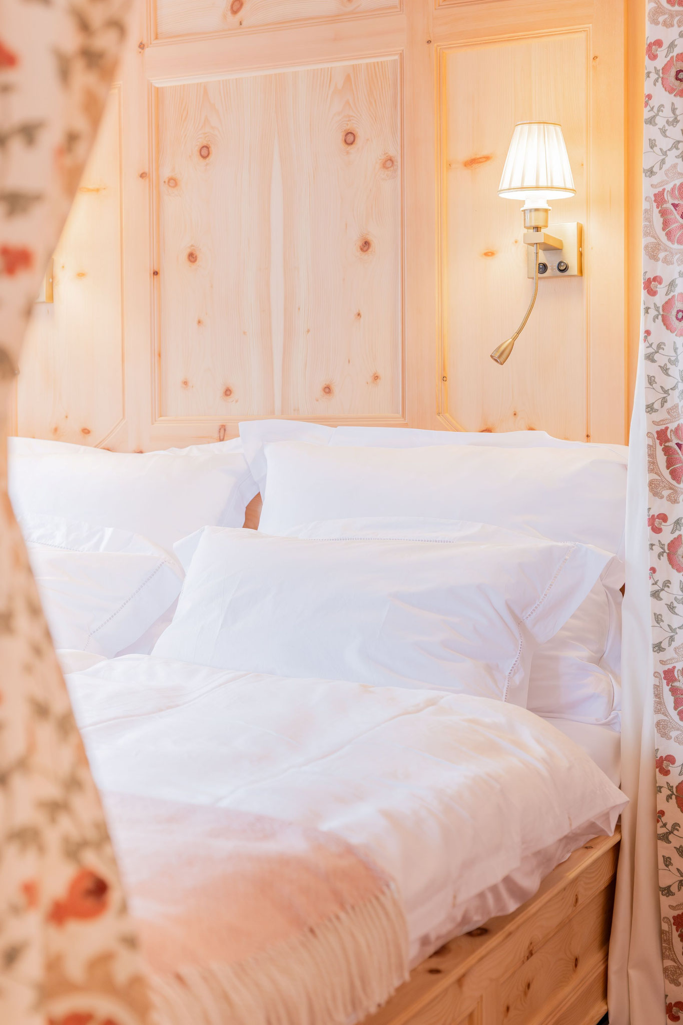 Zirbenholzbett mit weißer Bettwäsche und handbestickten Details